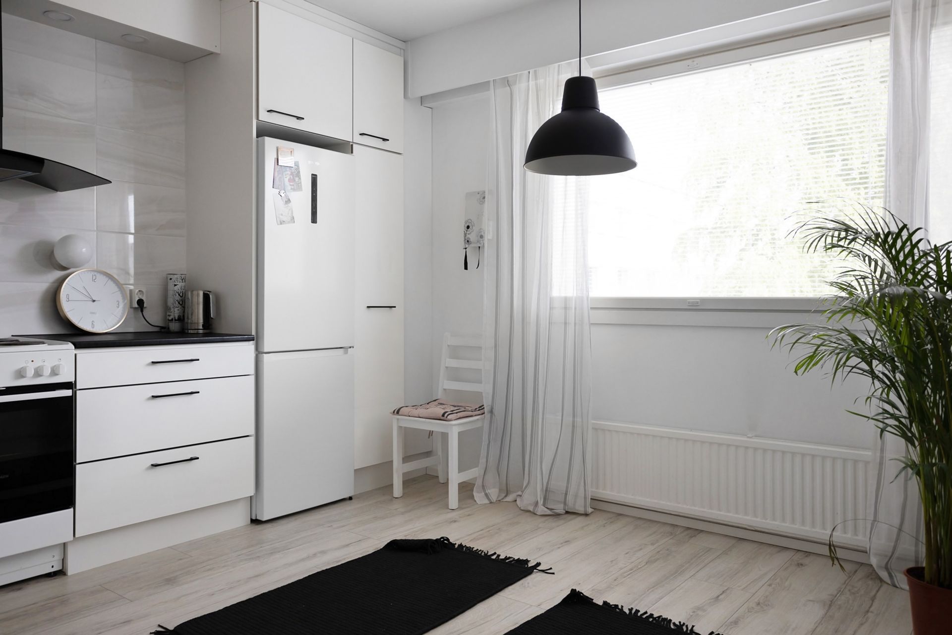 Cuisine blanche et lumineuse avec suspension noire et grande fenêtre