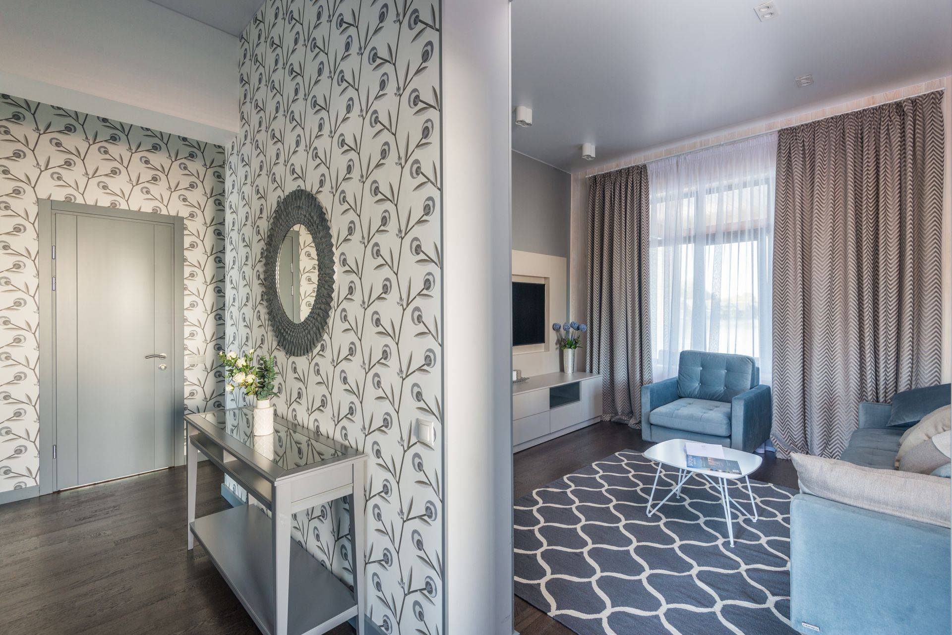 Entrée avec papier peint à motifs clairs, console et miroir rond